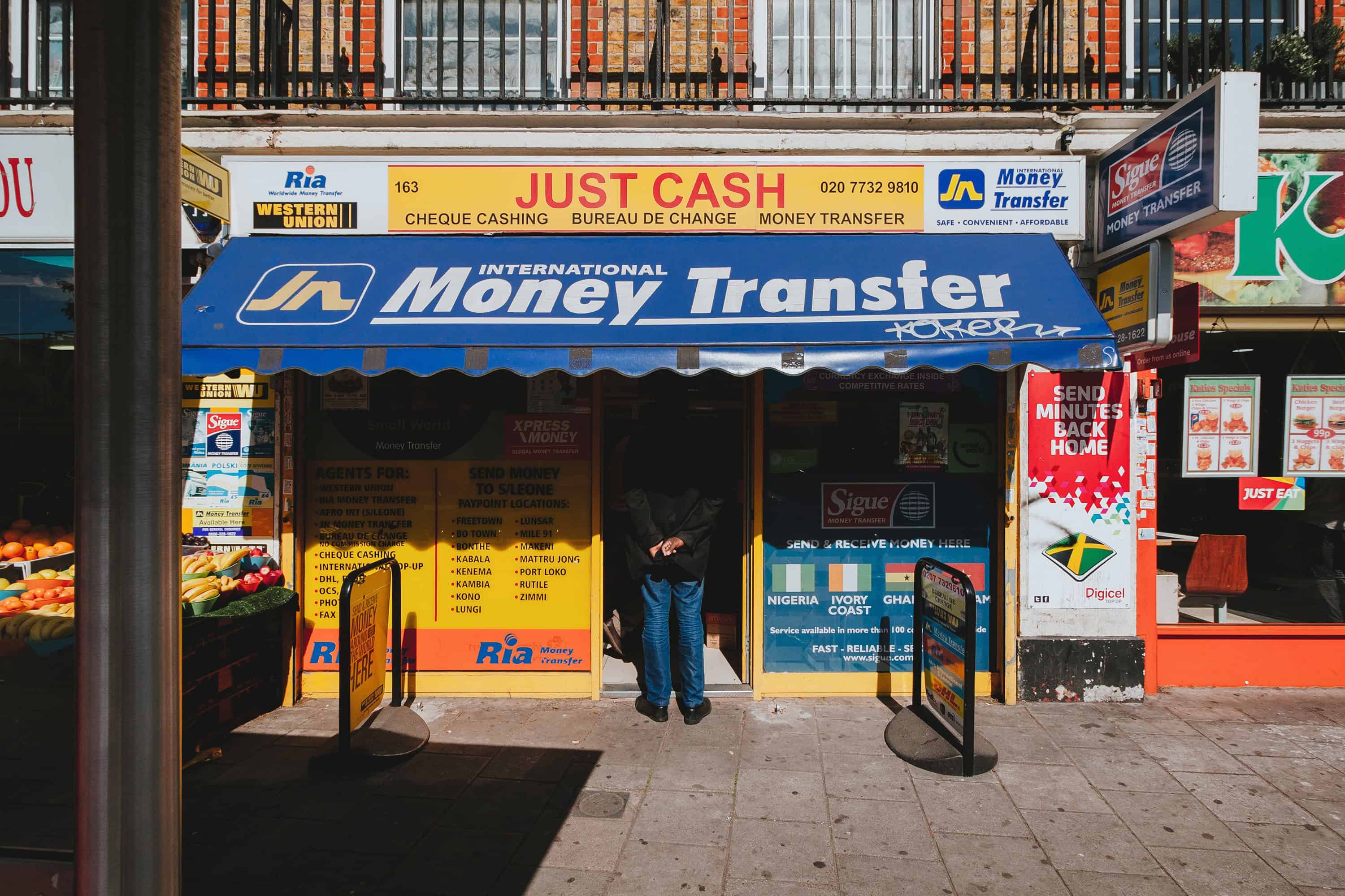 A man stands with his hands behind his bank at an International Money Transfer shop